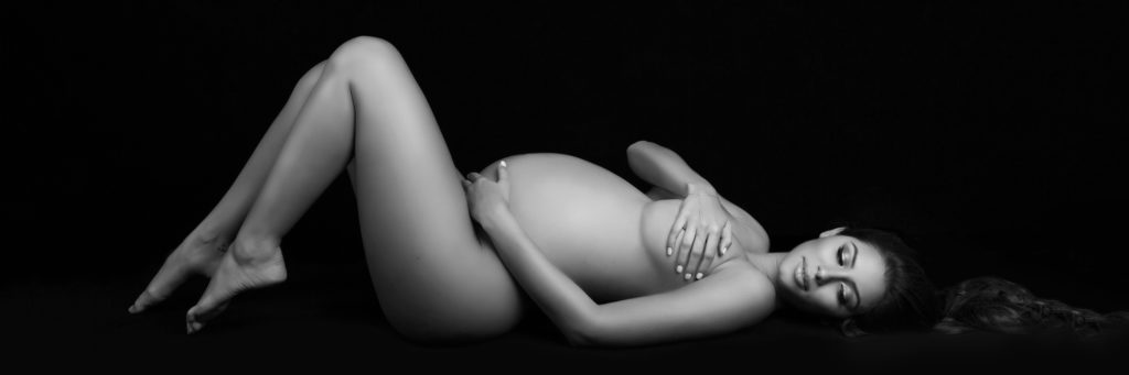 pregnant woman laying on back with knees bent looking down