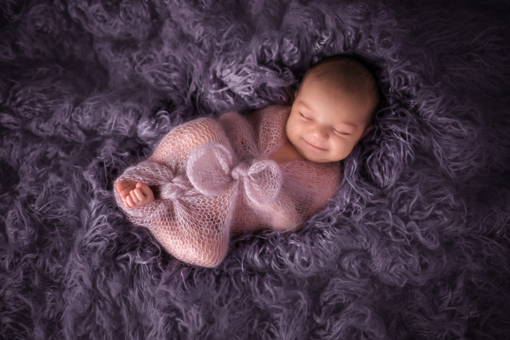 smiling newborn baby photo with purple fur background