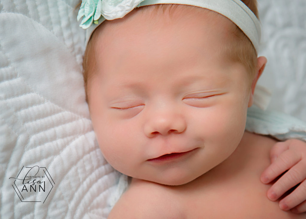 smiling newborn baby wearing white satin headband