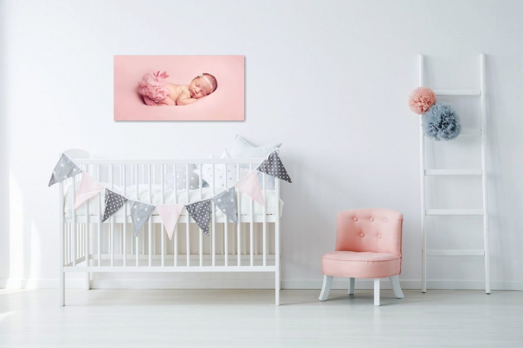 modern baby nursery with portrait of newborn baby above crib
