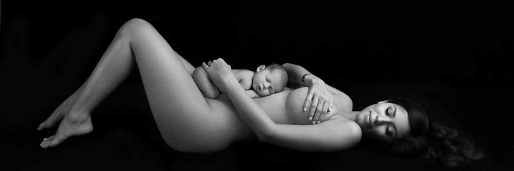 nude woman laying on back with newborn baby on stomach