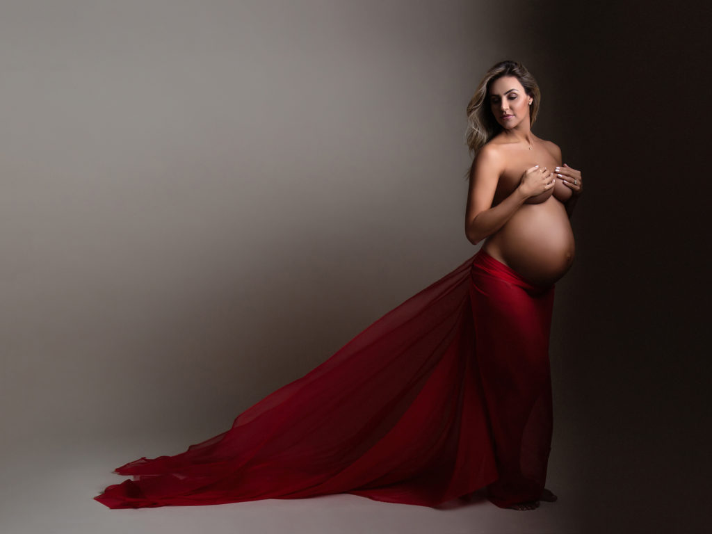 pregnant mom with red fabric showing off her baby bump in maternity photoshoot