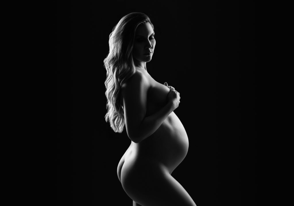 pregnant mom with long hair posing peacefully in black and white photo 