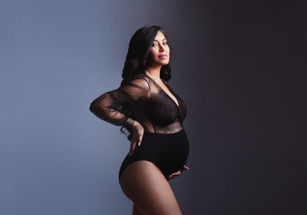 pregnant model poses in a black lace leotard