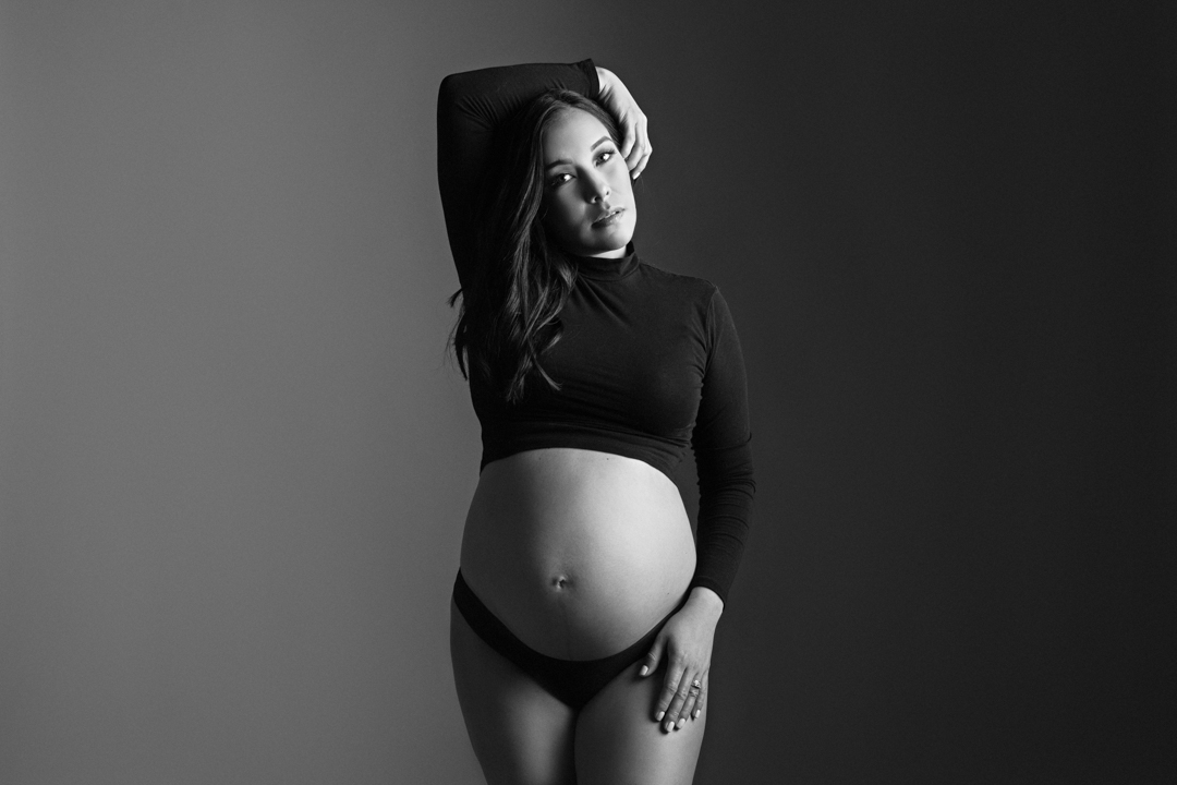 black and white photo of a pregnant model posing in a cropped black shirt