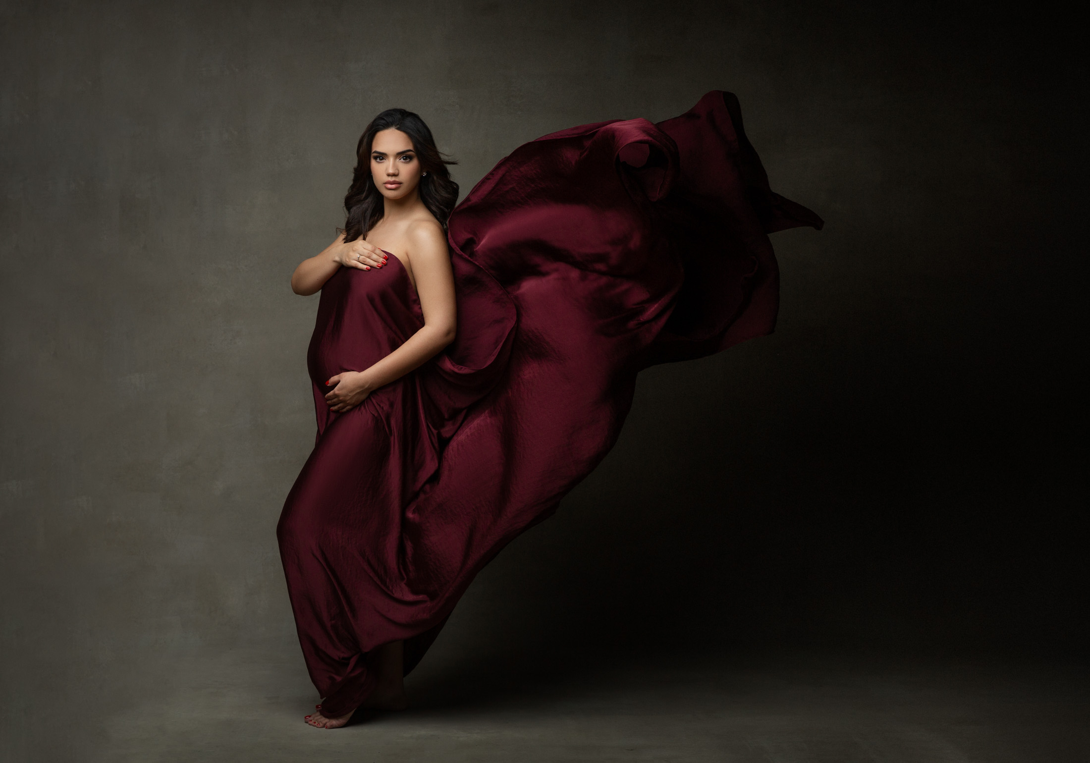 pregnant woman with burgundy silk fabric flowing