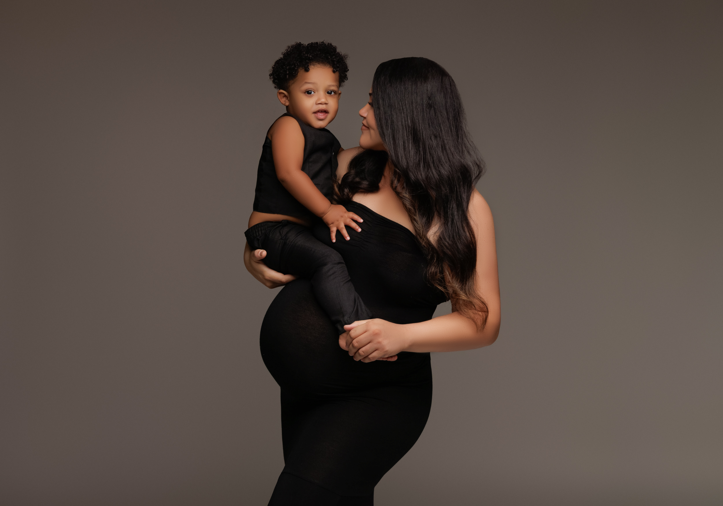 pregnant woman in black dress holding her toddler