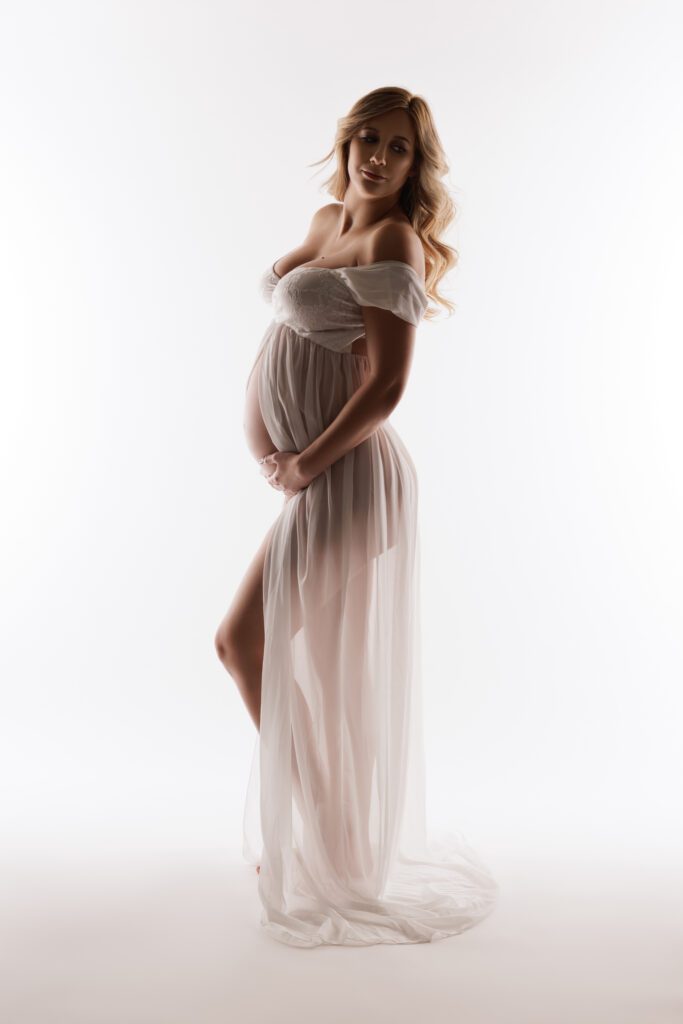 pregnant woman in white dress with white backdrop