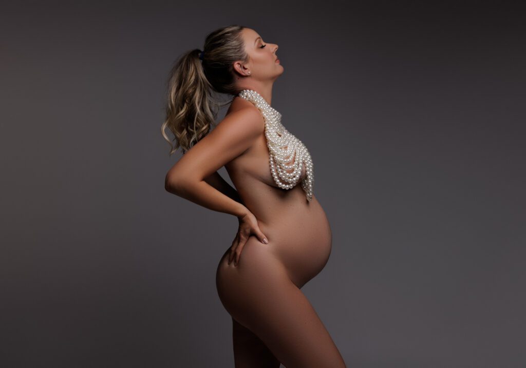 pregnant woman posing with pearl top with grey background