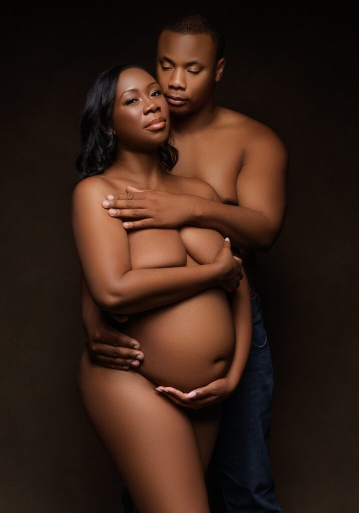 couple of man and pregnant woman standing posing with brown backdrop