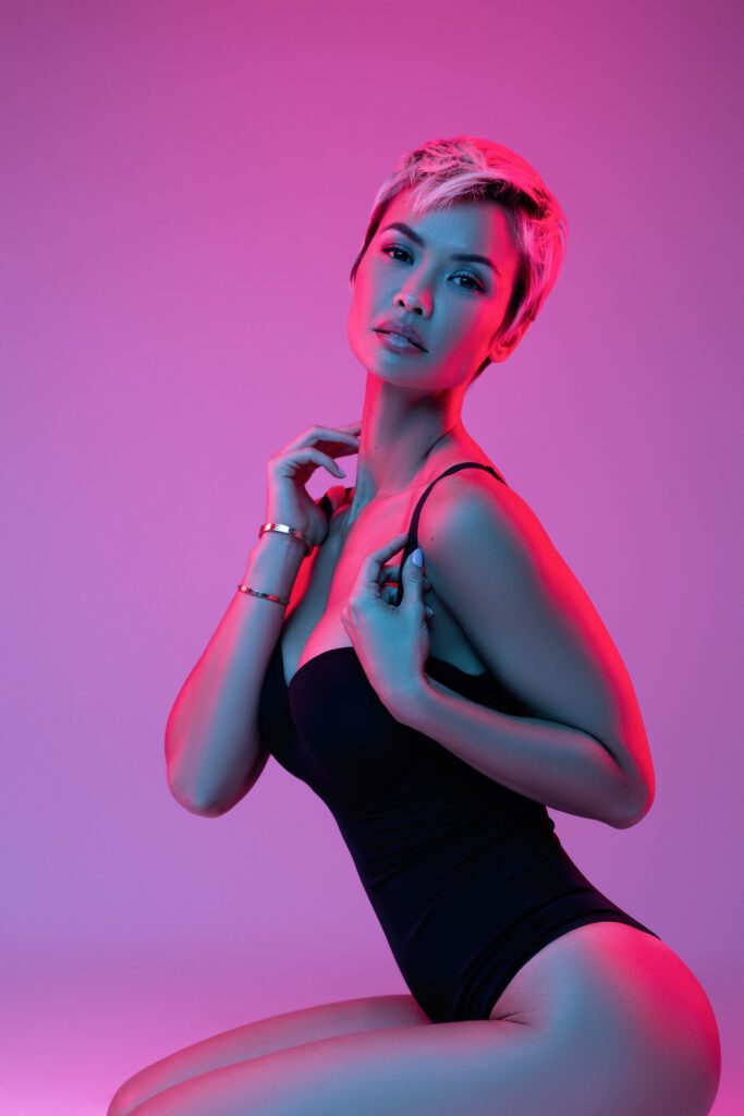 woman in black bodysuit with colorful lighting in studio