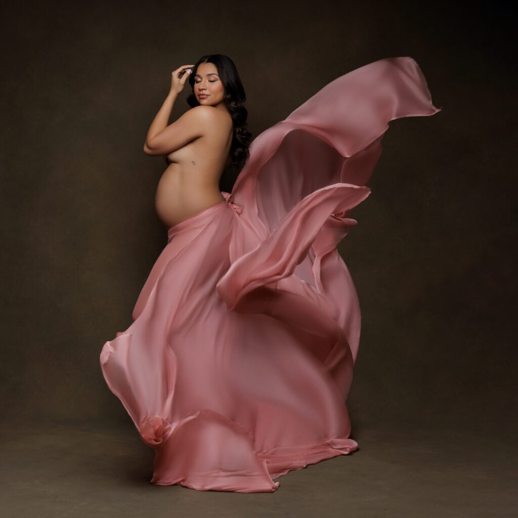 maternity shoot of woman with pink silk flared up