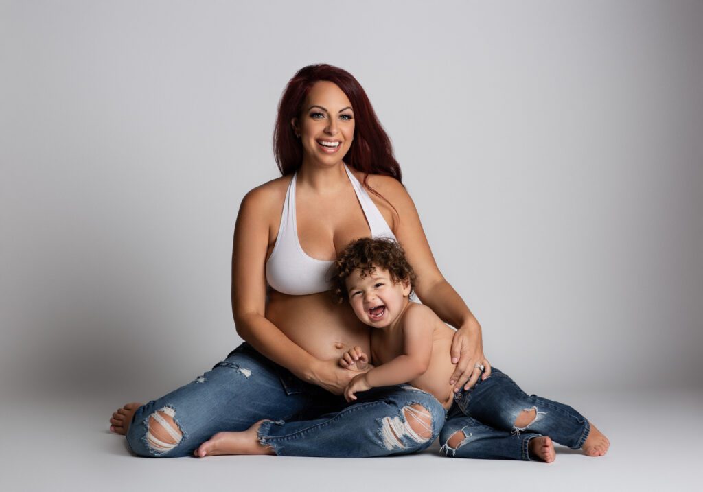 pregnant woman posing with infant child