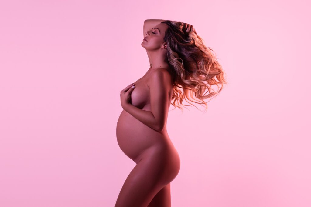 pregnant woman posing with pink lighting